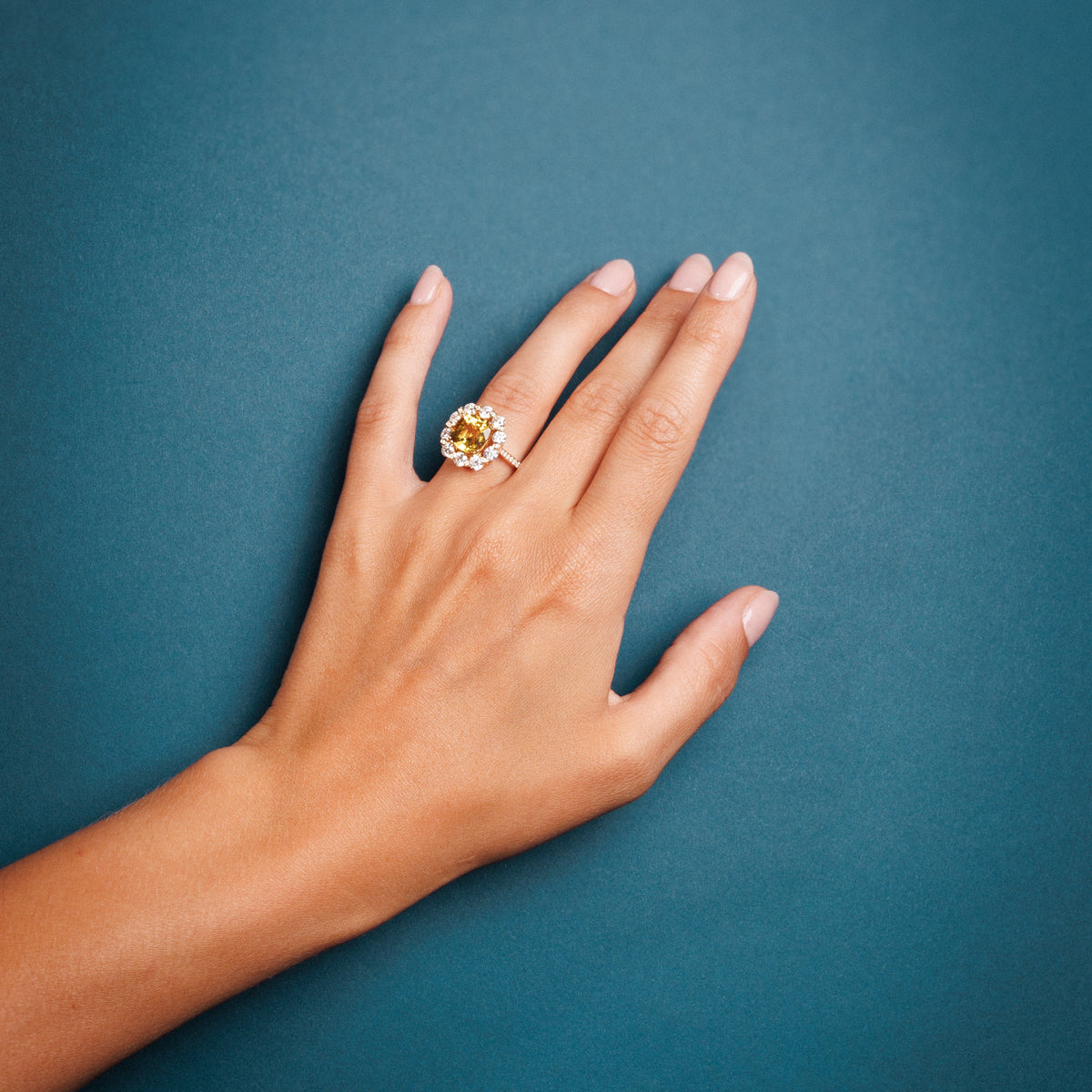 main de femme qui porte une bague saphir jaune et diamants 