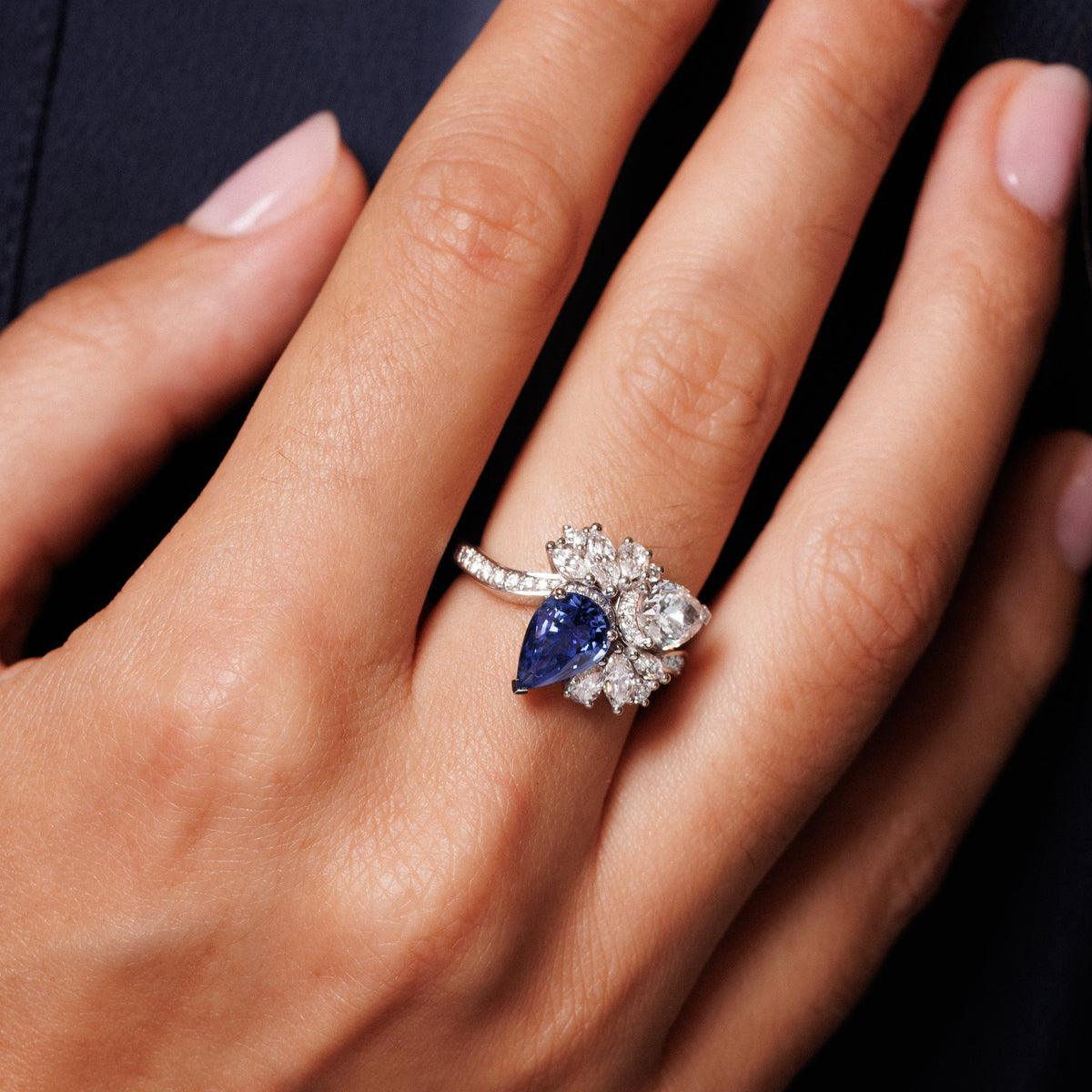 Femme qui porte une bague saphir taille poire et diamants naturels 