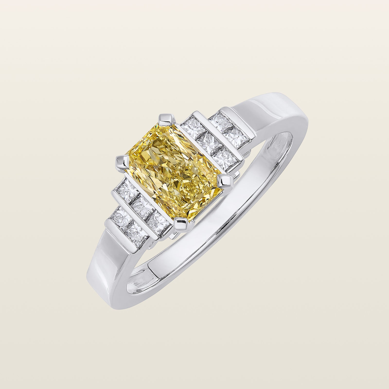 Bague en or blanc sertie d’un diamant fancy yellow taille radiant entouré de diamants taille princesse sur un anneau large et structuré