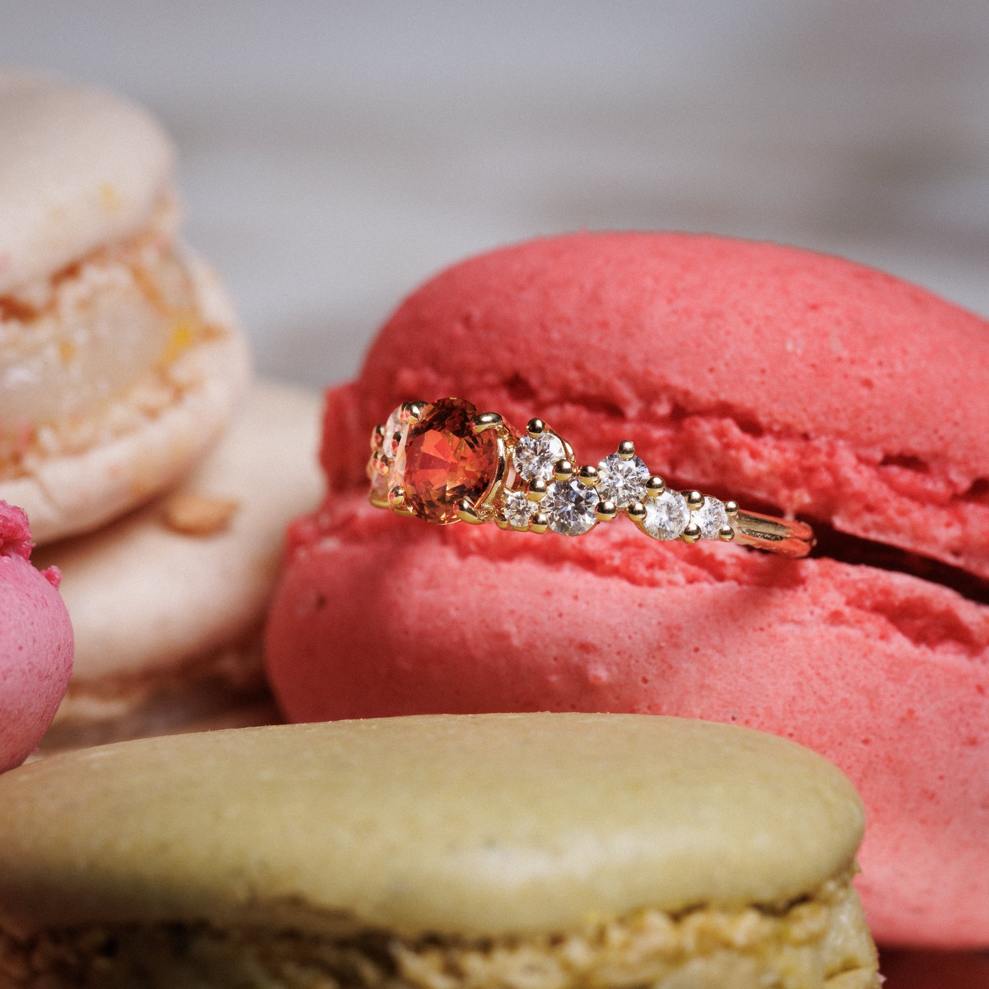 bague nuage saphir orange diamants naturels or jaune posée sur un macaron rose 