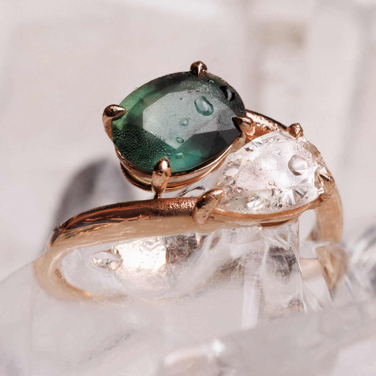 bague avec deux pierres un saphir vert et un diamants posee sur des glacons