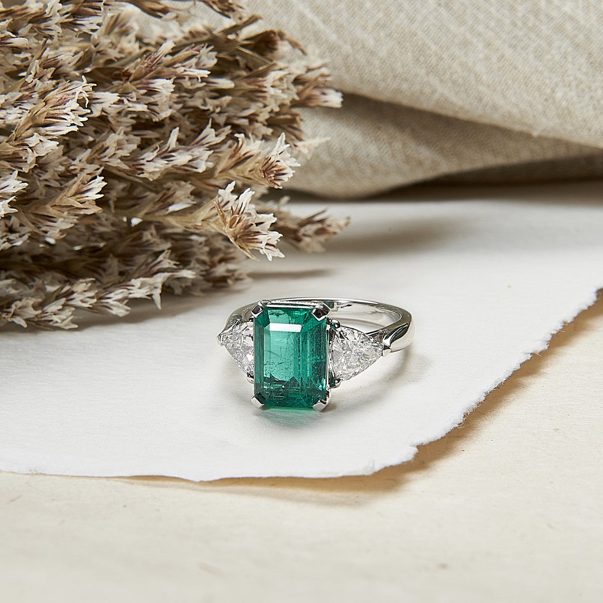 une bague avec une emeraude et un diamant pose sur une table 