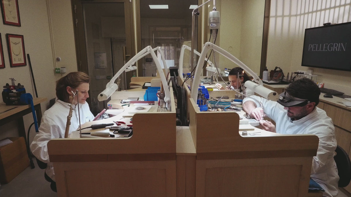 Artisans joailliers travaillant dans un atelier visible depuis la boutique, façonnant des pièces de haute joaillerie dans un espace lumineux, symbole de savoir-faire artisanal et de fabrication éthique.